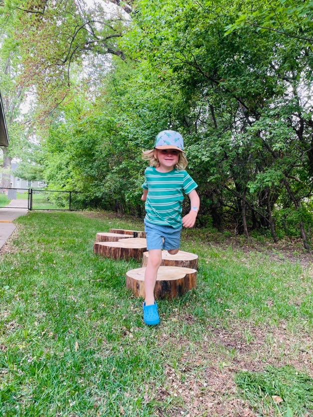 child jumping off tree stump path